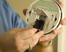 Graphic showing a battery being installed in a smoke alarm
