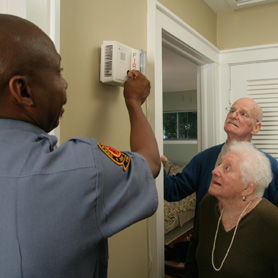 Graphic showing a woman testing a smoke alarm while young man watches 