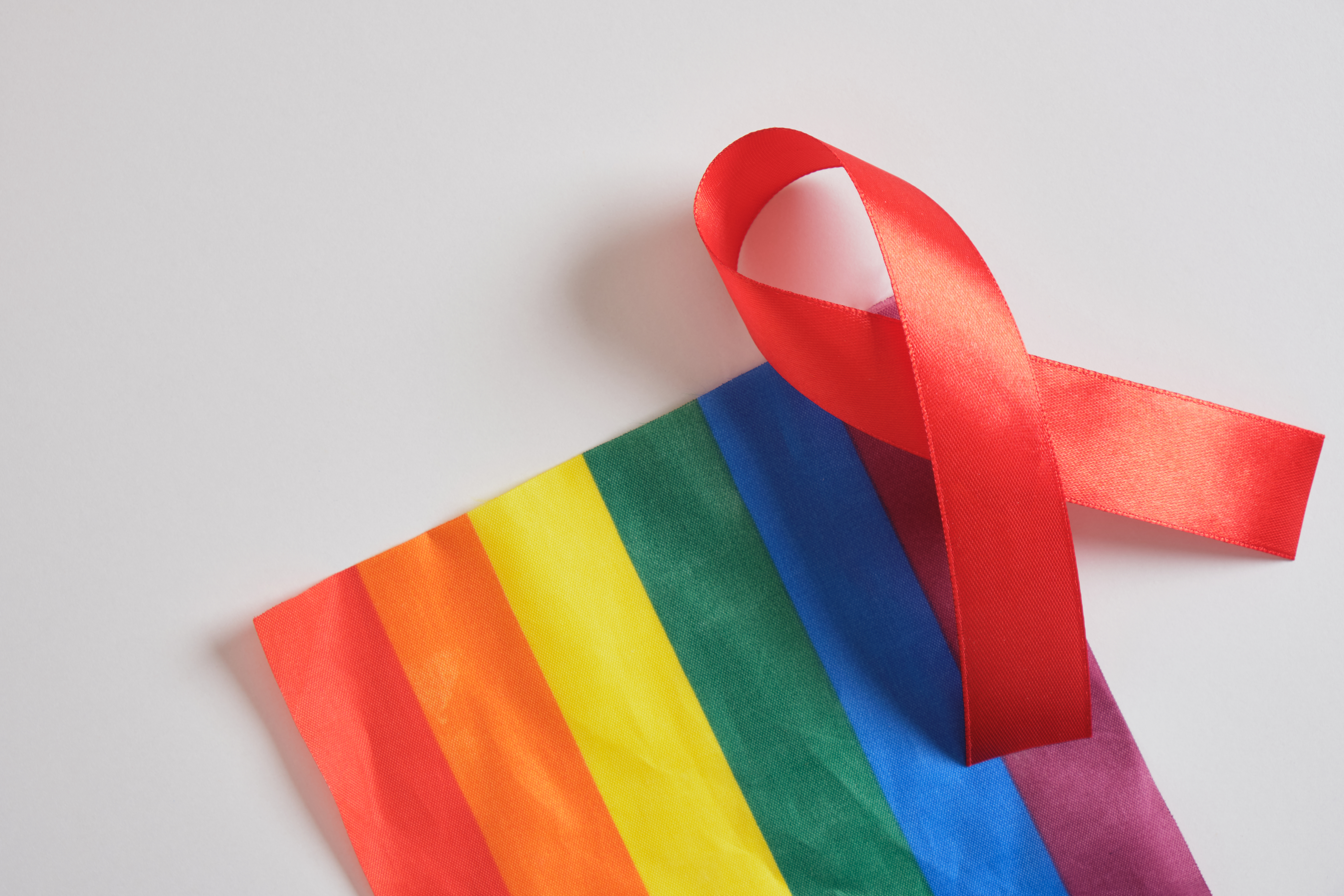 red ribbon placed on top of pride flag