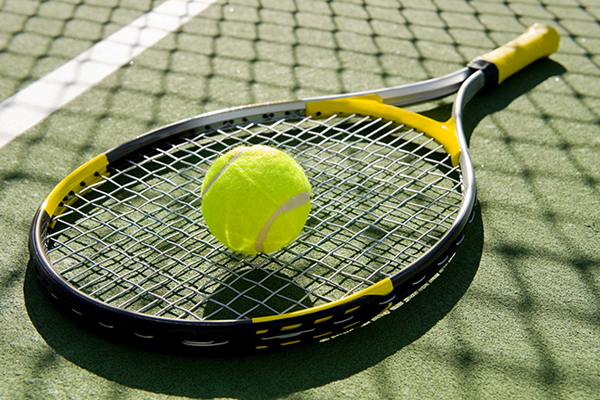 a tennis racket and tennis ball laying on a tennis court
