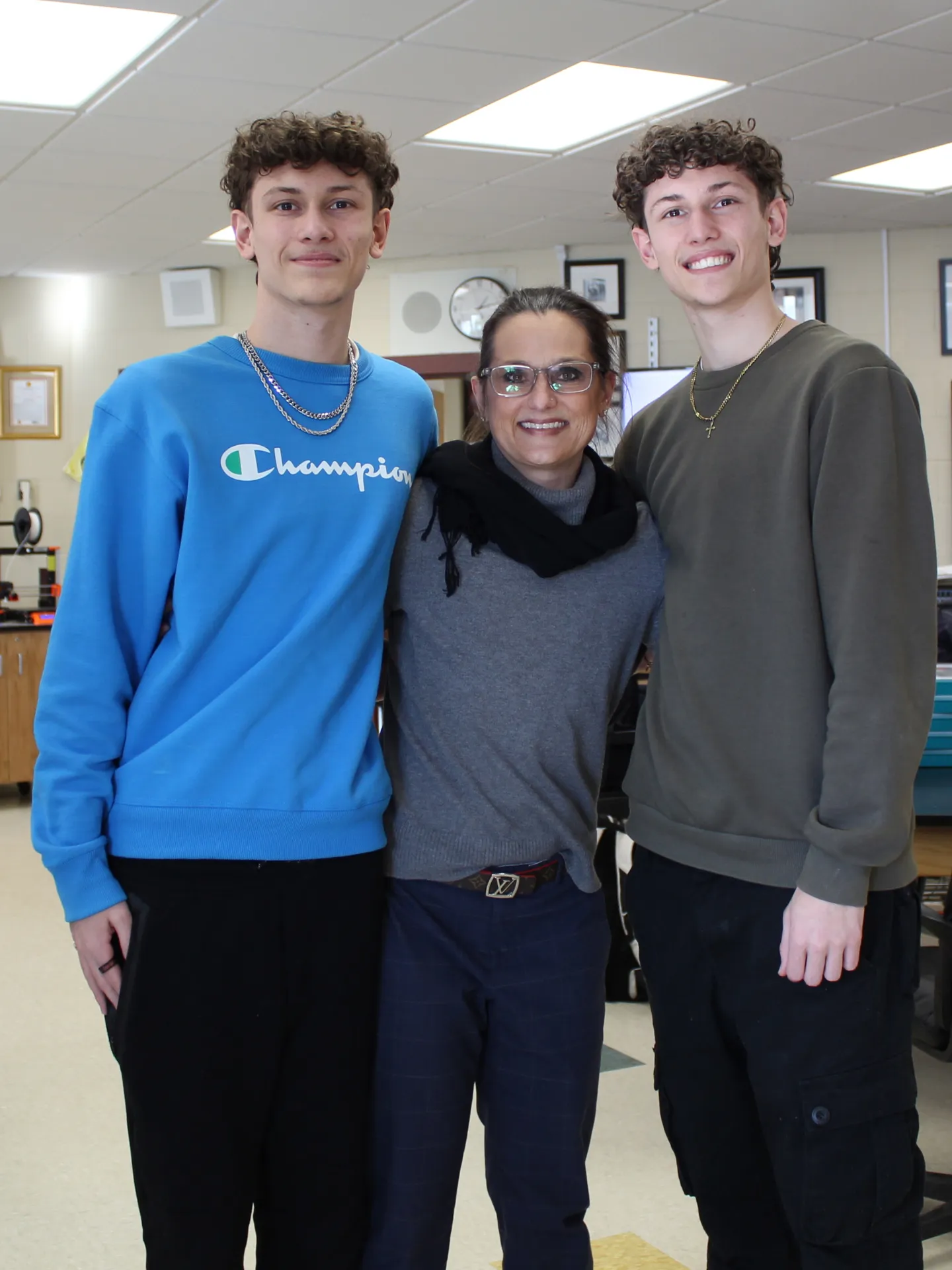 a pair of teens standing with an adult